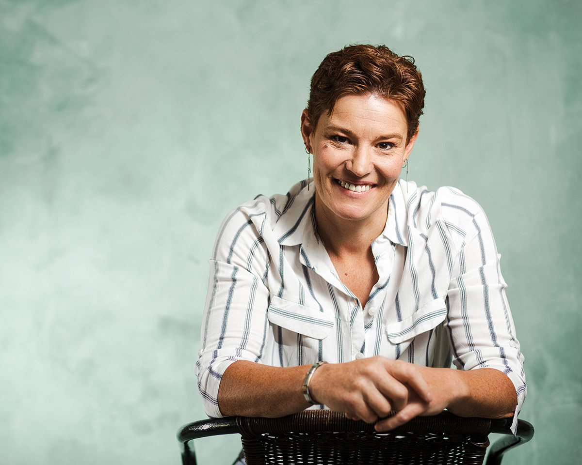 A smiling client in a striped shirt, seated on a chair against a green backdrop