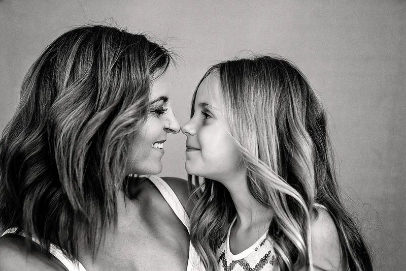 A black and white portrait of a mother and daughter, nose to nose